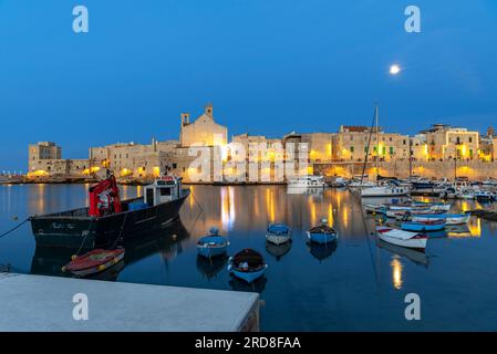 Vollmondnacht über dem beleuchteten mittelalterlichen Dorf Giovinazzo mit touristischem Yachthafen im Vordergrund, Provinz Bari Stockfoto