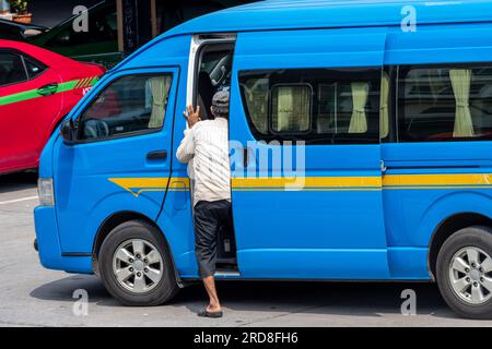 Ein Mann steigt aus dem Kleinbus - Gemeinschaftstaxi, ein traditioneller öffentlicher Nahverkehr für Menschen in Thailand Stockfoto