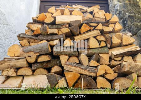 Brennholz auf einem Haufen vor einem Tor im Hof. Stockfoto