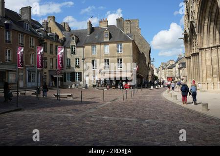 Das Stadtzentrum vor der Kathedrale, mit Kopfsteinpflasterstraße und Bayeux Banners. Bayeux, Frankreich Stockfoto