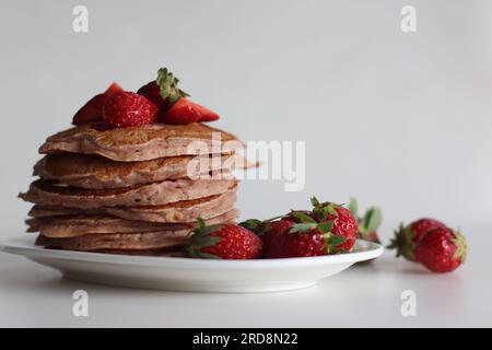 Buttermilch-Erdbeerpfannkuchen. Eine fröhliche Version von Pfannkuchen mit Erdbeersauce und frisch geschnittenen Erdbeeren, die dem Pfannkuchenteig hinzugefügt wurden. Auf Peitsche geschossen Stockfoto