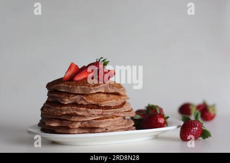 Buttermilch-Erdbeerpfannkuchen. Eine fruchtige Version von Pfannkuchen mit Erdbeersauce und frisch geschnittenen Erdbeeren, die dem Pfannkuchenteig hinzugefügt werden. Auf Whi geschossen Stockfoto