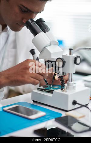 Nahaufnahme eines Technikers mit Mikroskop bei der Untersuchung der Festplatte Stockfoto