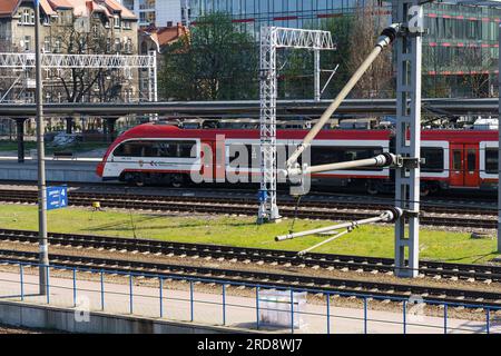 Poznan, Polen - 21. April 2023: Moderner weißer und roter Regionalzug der Wielkopolska Railway fährt in Richtung Bahnhof. Blick von oben. Stockfoto