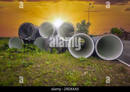 Große Plastikrohre für die Wasserversorgung liegen auf der Straße in der Stadt. Kunststoffrohre mit großem Durchmesser für städtische Infrastruktur. Abwasserrohre. Stockfoto