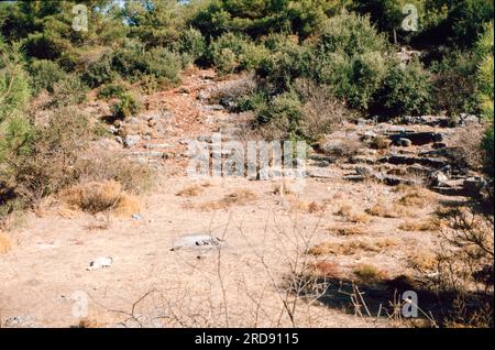 Überreste eines Theaters in Panionium (Panionion) - Ruinen des Ionischen Heiligtums, das Poseidon Helikonios und dem Treffpunkt der Ionischen Liga gewidmet ist. Es war auf der Halbinsel des Mt. Mycale, etwa 100 Kilometer (62 Meilen) südlich von Smyrna - jetzt Izmir, in der Türkei. Archivscan von einer Dia. Oktober 1985. Stockfoto