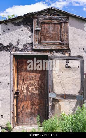 Alte Ständer des Lagerschuppens mit Dachbodenklappe über der unteren Tür verwittert. Stockfoto