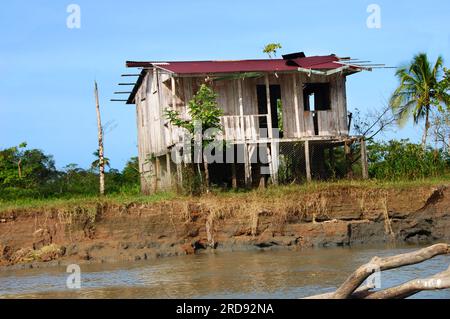 Costa Rica Home sitzt am Flussufer und ist erhöht, für die Regenzeit. Tin Roof ist verfallen und Home sieht verlassen aus. Stockfoto