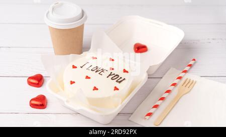 Kleiner Bento-Kuchen im Karton auf weißem Holzhintergrund Stockfoto