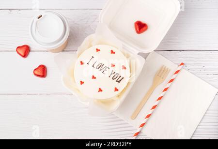 Flach liegend mit Bento-Kuchen im Karton auf weißem Holzhintergrund Stockfoto