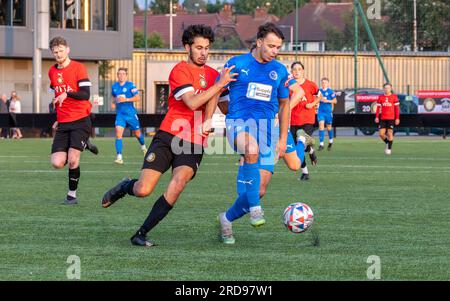 Der Warrington Rylands-Spieler Scott Bakkor kontrolliert den Fußball unter dem Druck eines Stockport Town Verteidigers im Stockport Sports Village auf einem 3G-Platz Stockfoto