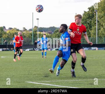 Warrington Rylands-Spieler Adam Side92 sieht sich einen High Ball an, der von einem Stockport Town-Verteidiger im Stockport Sports Village auf einem 3G-m-Spielfeld unter Druck gesetzt wird Stockfoto