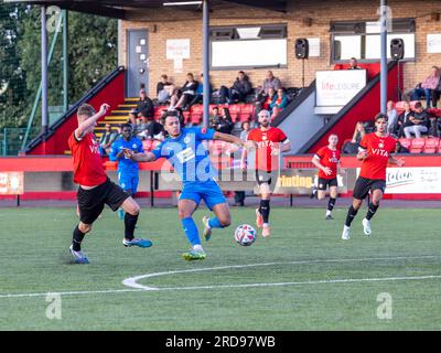 Warrington Rylands-Spieler Scott Bakkor bereitet sich auf ein Tor vor, das von einem Stockport Town-Verteidiger im Stockport Sports Village auf einem 3G-cm-Spielfeld unter Druck gesetzt wird Stockfoto