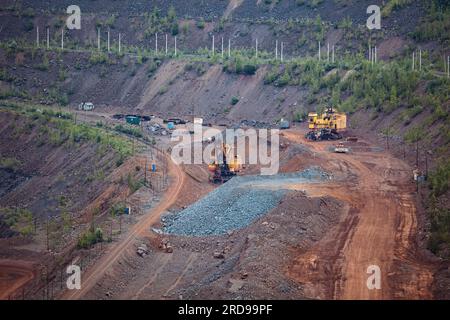 Hydraulikbagger und Kipplaster, die im Tagebau in Bergbau- und Verarbeitungsanlagen Erdbewegungsarbeiten durchführen. Stockfoto