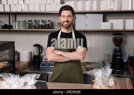 Glücklicher Verkäufer an der Kasse in der Bäckerei Stockfoto
