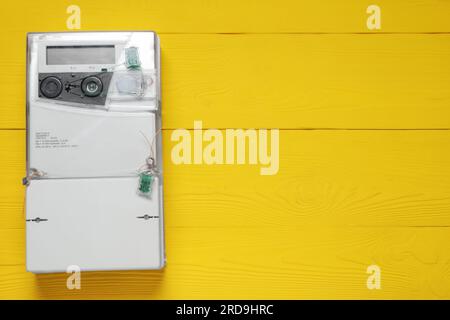Stromzähler an gelber Holzwand, Platz für Text Stockfoto