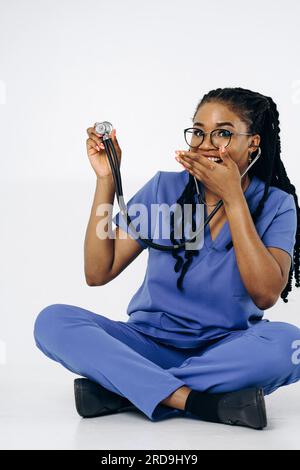 Porträt einer lächelnden Krankenschwester oder Ärztin in blauen Bürsten Uniform sitzendes Stethoskop Stockfoto