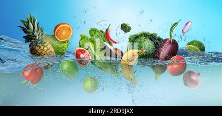 Viele Früchte und Gemüse fallen vor blauem Hintergrund ins Wasser Stockfoto