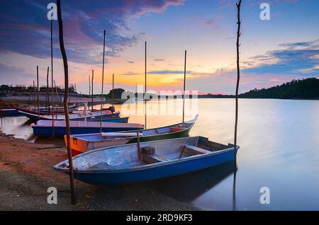 Eine Reihe Fischerboote am Fluss bei Sonnenuntergang. Stockfoto