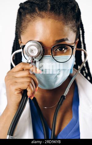 Wunderschöne afroamerikanische Ärztin mit Maske und Stethoskop Stockfoto