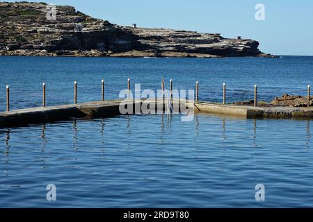 An der Long Bay, Malabar Ocean Pool, mit Blick auf eine Zunge von felsigem Landzunge, blauem Wasser, blauem Himmel und Sonnenschein in Sydney, Australien Stockfoto