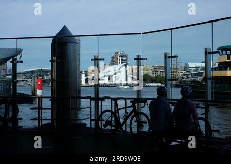 Pendler blicken durch die Glaswand auf dem Fähranleger in Barangaroo Sydney mit Darling Harbour und Maritime Museum im Hintergrund Stockfoto
