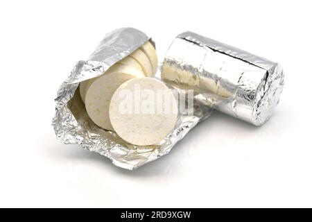 Brausetabletten oder Kohlentabletten, die vor dem Füllen in einen dichten Röhrchenbehälter in Aluminiumfolie verpackt werden. Stockfoto