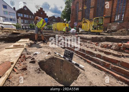 Winsen, Deutschland. 17. Juli 2023. Mitarbeiter des Archäologischen Museums Hamburg graben auf dem Kirchenvorplatz St. Marienkirche in Winsen/Luhe (Bezirk Harburg). Bevor im Rahmen des Stadterneuerungsprojekts „Winsen 2030“ ein Wasserspiel errichtet wird, wird hier die Baugeschichte entziffert. Seit dem Mittelalter befinden sich das Rathaus und ein städtischer Glockenturm an diesem Standort. (Zu dpa: „Like a Puzzle“ – Sonderausgrabungen im Stadtzentrum von Winsen“) Kredit: Ulrich Perrey/dpa/Alamy Live News Stockfoto