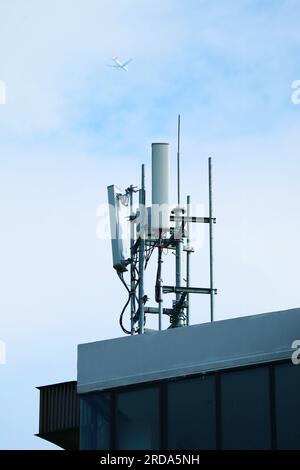 Handyantennen auf dem Dach mit Flugzeug fliegt auf bewölktem Himmel Stockfoto