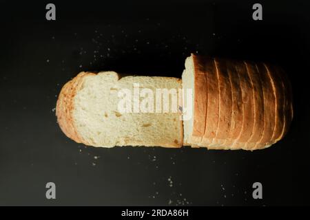 Geschnittenes Brot auf schwarzem Hintergrund. Draufsicht Stockfoto