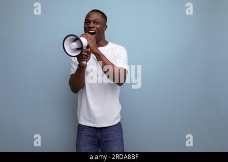 Ein positiver, gutaussehender, dunkelhäutiger, junger amerikaner in einem weißen T-Shirt mit Megafon Stockfoto