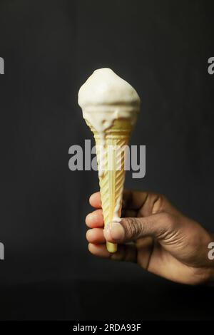 Eiskegel in der Hand auf schwarzem Hintergrund, Nahaufnahme. Stockfoto