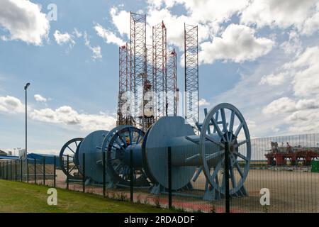 Große Blue Cable Rollen im Vordergrund einer Baustelle für Bohrinseln in Invergordon, Schottland. Stützbeine im Hintergrund aufbocken. Stockfoto