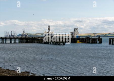 Holzstege in Invergordon mit Ölbohrplattform und Bohrinseln im Hintergrund. Stockfoto