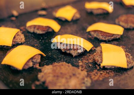 Hackfleisch mit Käse für Hamburger auf Flat Top Grill im Freien. Stockfoto