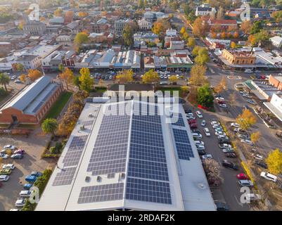 Blick aus der Vogelperspektive auf ein großes Dach mit Sonnenkollektoren, umgeben von historischen Gebäuden und Herbstbäumen in Castlemaine im Zentrum von Victoria, Australien Stockfoto