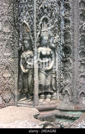 Ein paar Apsara-Tänzer, die auf eine Wand von Ta Prohm (Khmer: ប្រាសាទតាព្រហ្ម) geschnitzt wurden, einem Tempel in Angkor, Provinz Siem Reap, Kambodscha, erbaut in den Bayon s Stockfoto