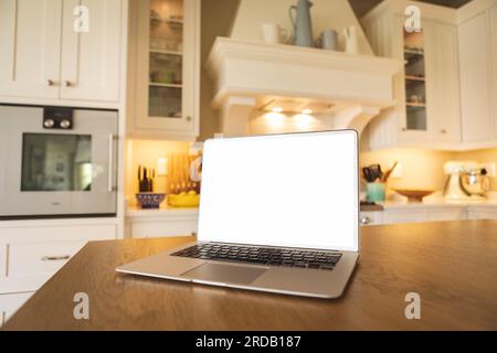 Laptop mit leerem weißen Bildschirm auf Holztisch mit Kamin im Hintergrund zu Hause, Kopierbereich Stockfoto