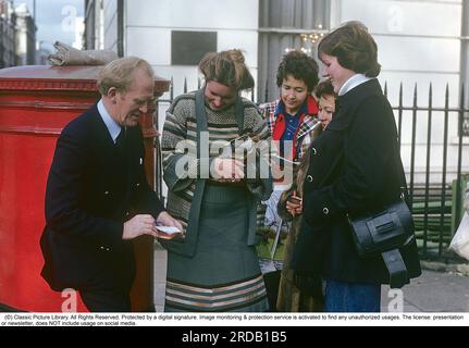 Gordon Jackson. dezember 1023 - 15. januar 1990. Der schottische Schauspieler erinnerte sich am besten an seine Rollen als Butler der Bellamys, Angus Hudson in der beliebten tv-Serie Upstairs, Downstairs, die zwischen 1971 und 1975 insgesamt 68 Episoden im fernsehen war. Und in der Rolle von George Cowley, dem Leiter der CI5 in der tv-Serie The Professionals in allen 57 Episoden der Sendung von 1977 bis 1983, obwohl die Dreharbeiten 1981 beendet wurden. Im Dezember 1989 wurde bei ihm Knochenkrebs diagnostiziert, er starb am 15. januar 1990 im Alter von 66 Jahren. im november 1975 schreibt er Autogramme in einer Londoner Straße. Von Kristoffersson Stockfoto