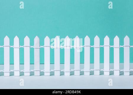 Weißer Holzzaun im Vintage-Stil auf grünem Hintergrund. Kleine gemalte, einfache Wälder dekorative Dorfzäunenreihe. Neu lackierter Retro-Langholz-barrie Stockfoto