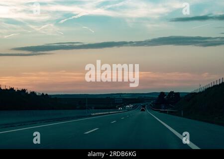 Blick auf den Sonnenuntergang auf der Autobahn mit bewölktem Himmel in österreich Stockfoto