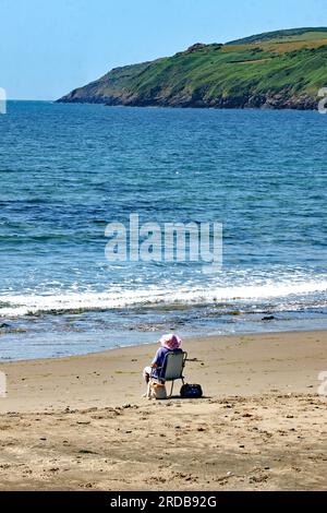 Das Leben ist ein Strand. Eine einsame Dame saß am Strand von Aberdaron und genoss die Aussicht Stockfoto