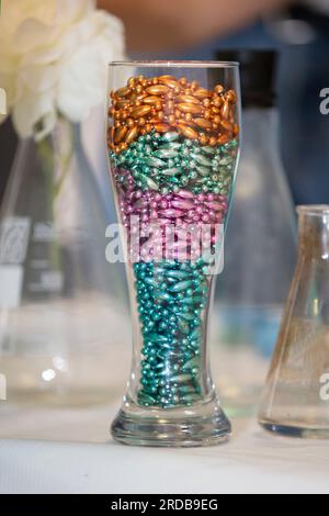Mehrfarbige Perlen für Laborversuche im Glasbecher. Stockfoto