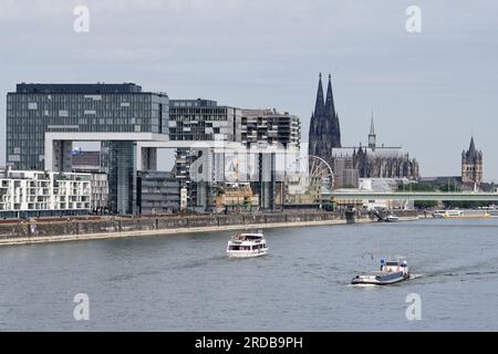 Köln, Deutschland Juli 18 2023: Exkursions- und Frachtschiffe auf dem rhein vor dem beeindruckenden Panorama von köln mit den Kranhäusern und der Katze Stockfoto