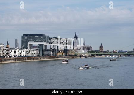 Köln, Deutschland Juli 18 2023: Exkursions- und Frachtschiffe auf dem rhein vor dem beeindruckenden Panorama von köln mit den Kranhäusern und der Katze Stockfoto