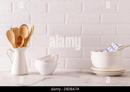 Küchenhintergrund in minimalistischem weißen Stil. Wunderschöne weiße Gerichte auf dem Hintergrund einer weißen Backsteinwand. Ökologisch saubere Küche. Keine Verschwendung Stockfoto