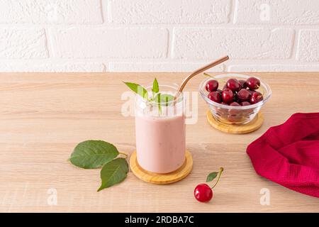 Frischer, hausgemachter Smoothie aus reifen Kirschen in einem stilvollen Glas auf einer Holzarbeitsfläche. Gesundes Bio-Getränk Stockfoto