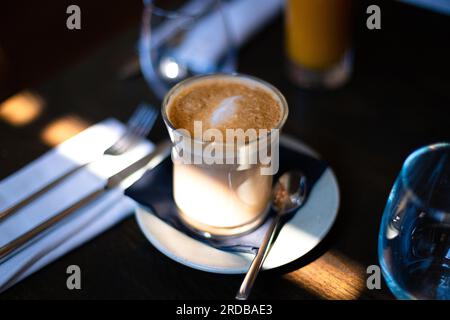 Latte-Kaffee in einem Glasbecher an einem Sonntagmorgen in einem Restaurant Stockfoto