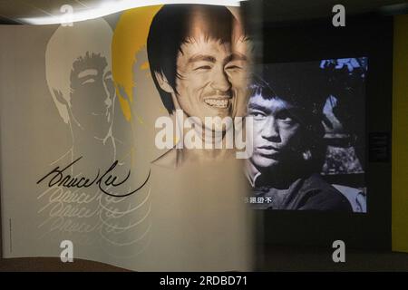 Riesige Poster von Bruce Lee sind in der Ausstellung zu sehen. Die Regierung Hongkongs feiert den 50. Todestag des Kampfkünstlers Bruce Lee mit einer bedeutenden Ausstellung im Hong Kong Heritage Museum. Die Ausstellung zieht Hunderte von Besuchern an und zollt dem Leben und Vermächtnis des legendären Kampfkünstlers Tribut und fasziniert die Besucher mit Ausstellungen, die seine außergewöhnlichen Leistungen und seinen kulturellen Einfluss zeigen. Gleichzeitig gehen einige Leute zur Statue von Bruce Lee in Tsim Sha Tsui und ehren sein Andenken mit herzlichen Gesten und Erinnerungen. Stockfoto