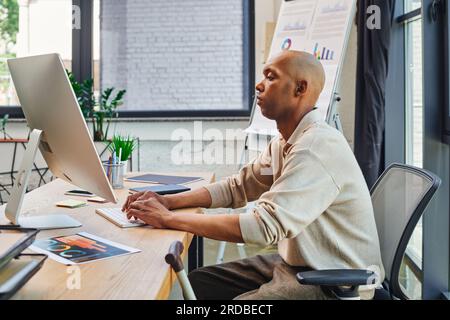 Inklusion, afroamerikanischer Mann mit Myasthenia gravis bei der Arbeit, mutiger und dunkelhäutiger Büroangestellter, der auf der Tastatur tippt und den Computer benutzt, schaut Stockfoto
